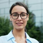 Casa Portrait of a smiling young woman wearing glasses in an outdoor setting.