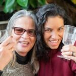 Casa Two joyful women enjoying a friendship toast outdoors with wine glasses in Portugal.